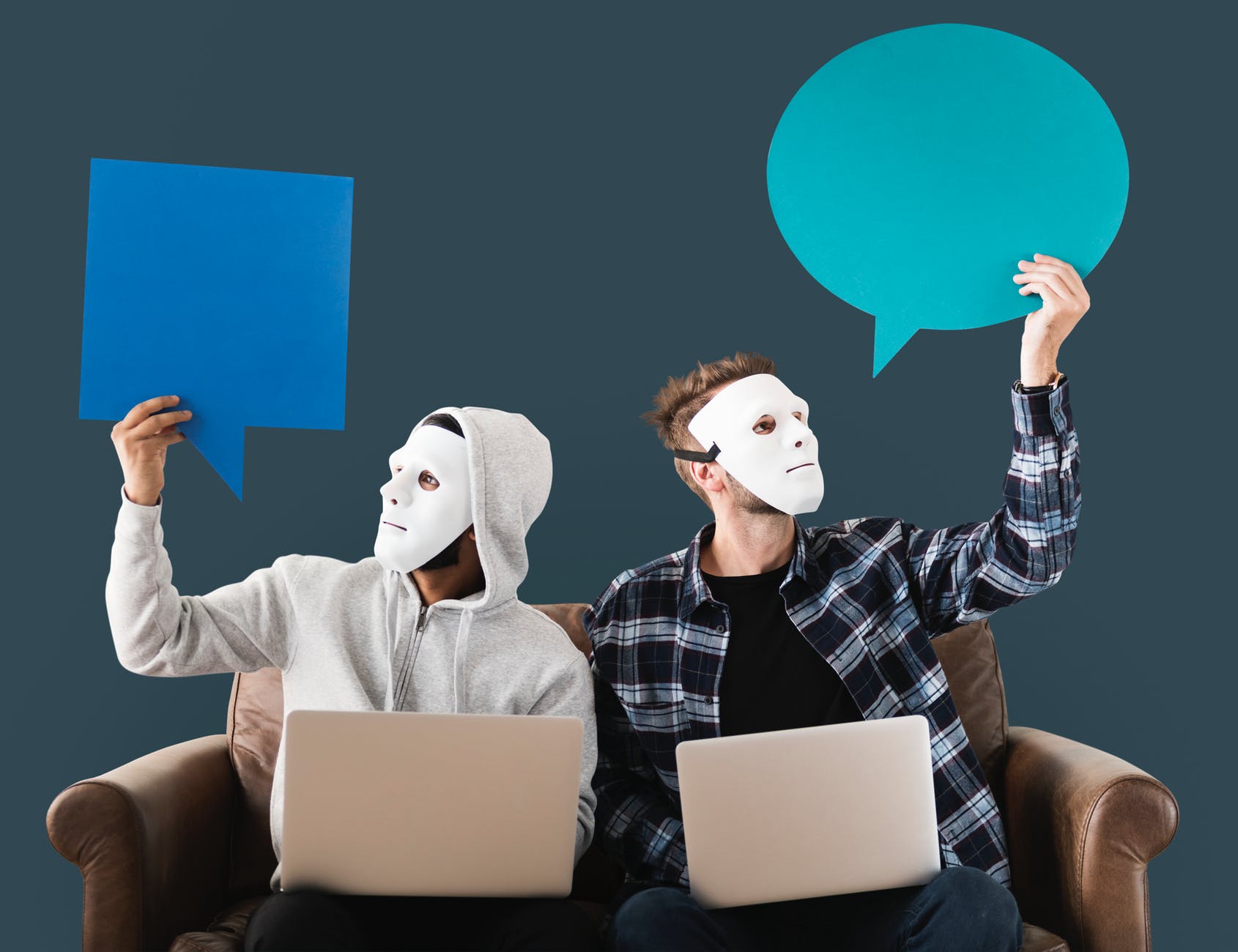 two men using white laptop computer sitting on brown wooden sofa