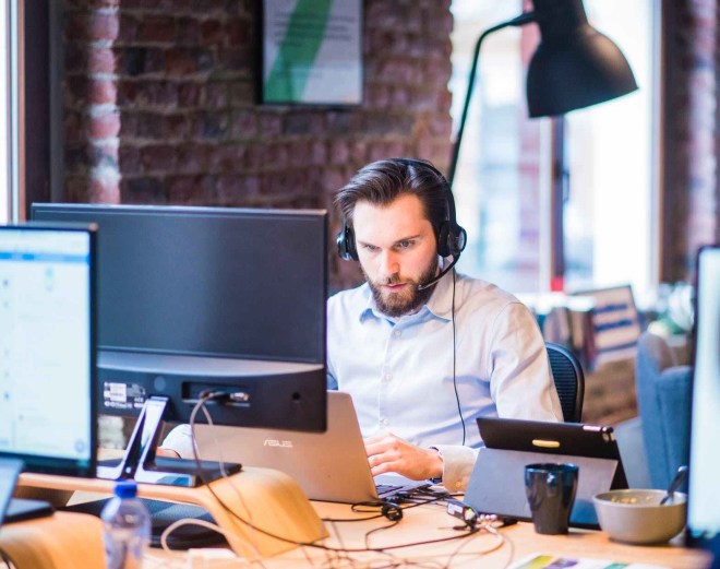 selective focus photo of man in official shirt sitting in office working on laptop