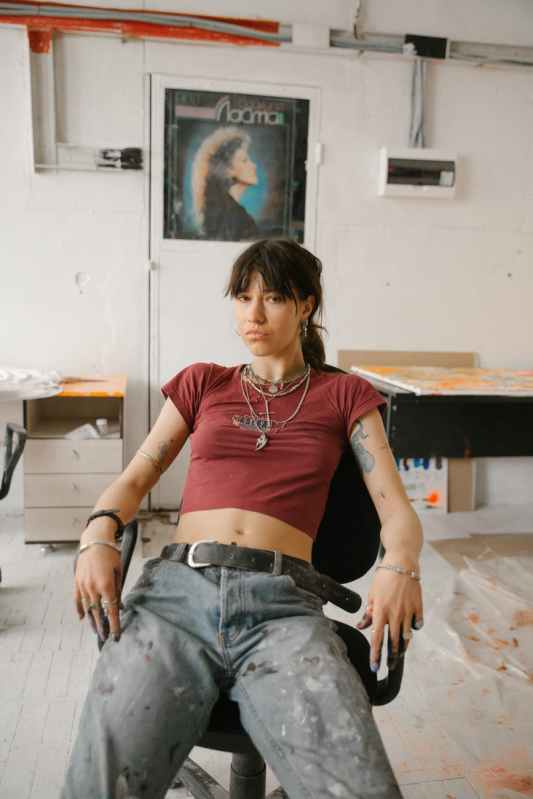 confident young woman sitting on office chair in old aged artist workshop