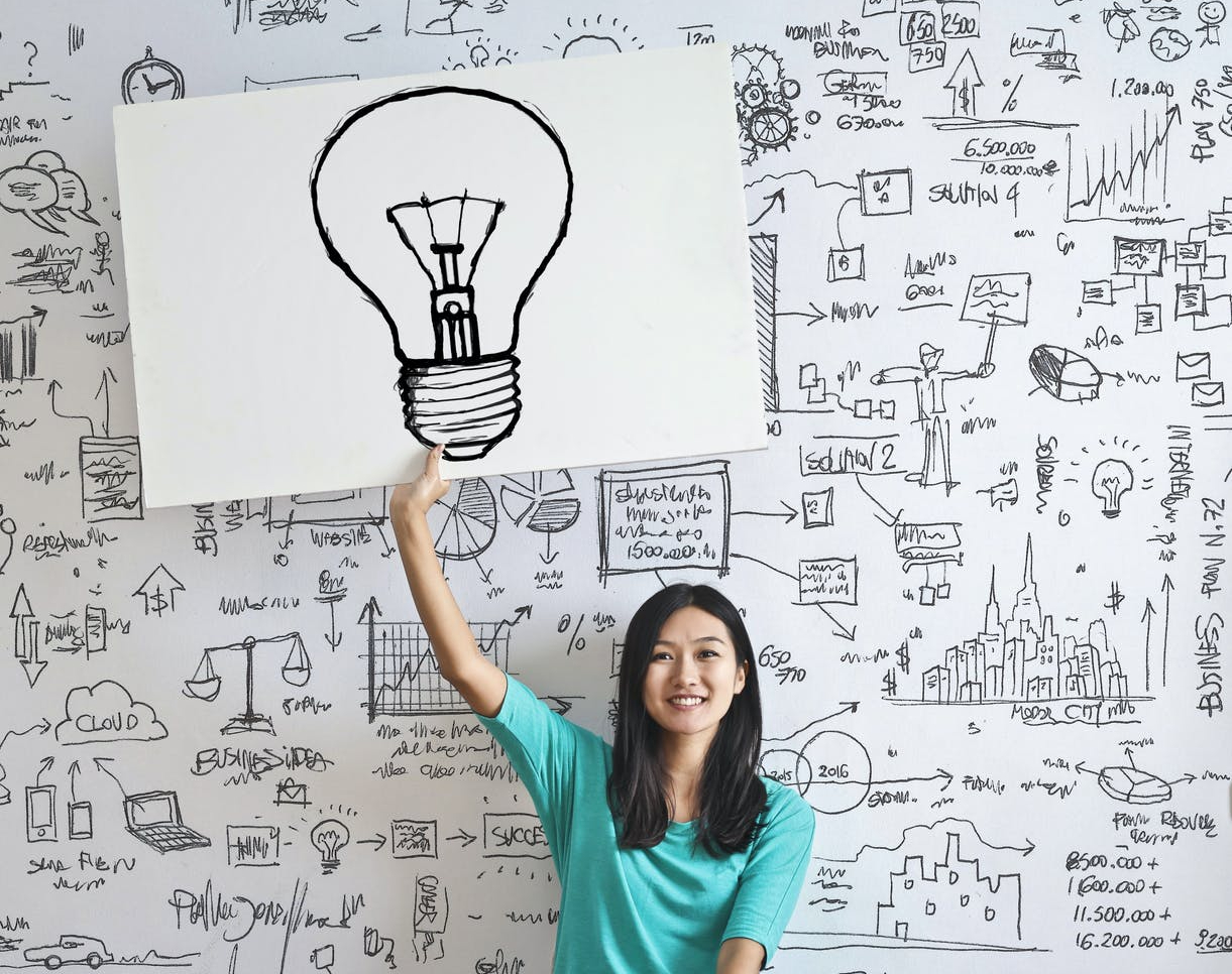 woman draw a light bulb in white board